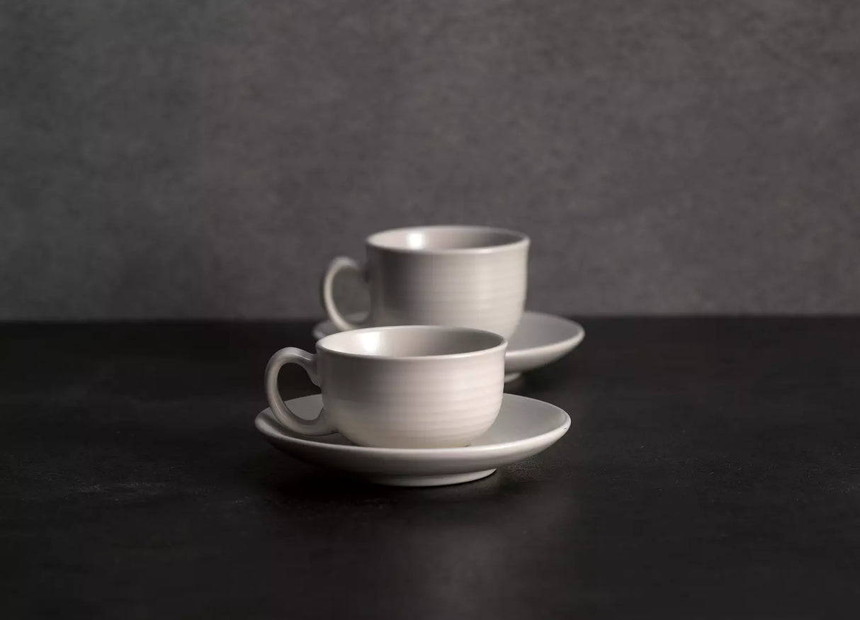 Two coffee cups and saucers on grey background