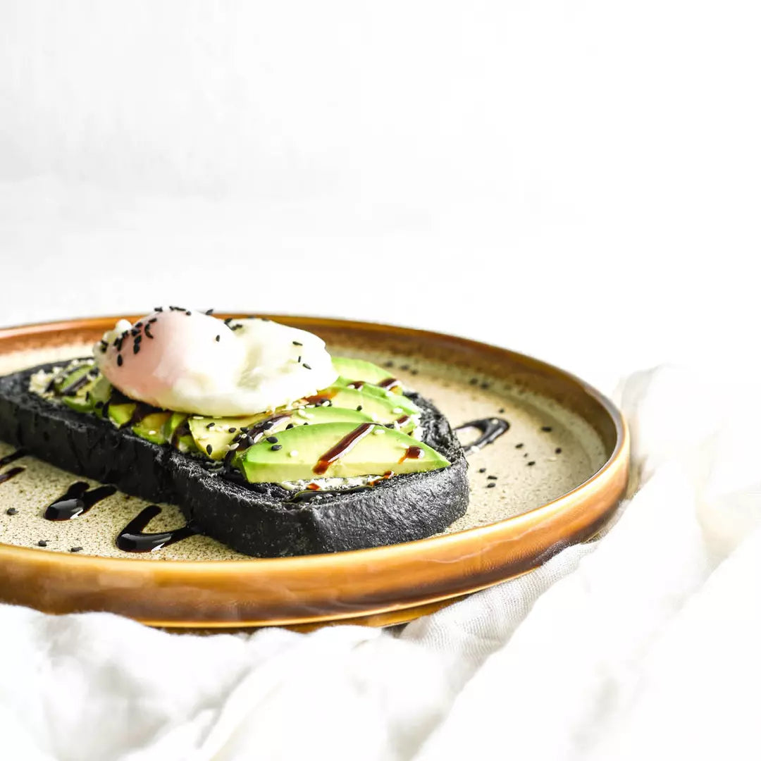 Medium sized brown plate with smashed avo displayed on white background