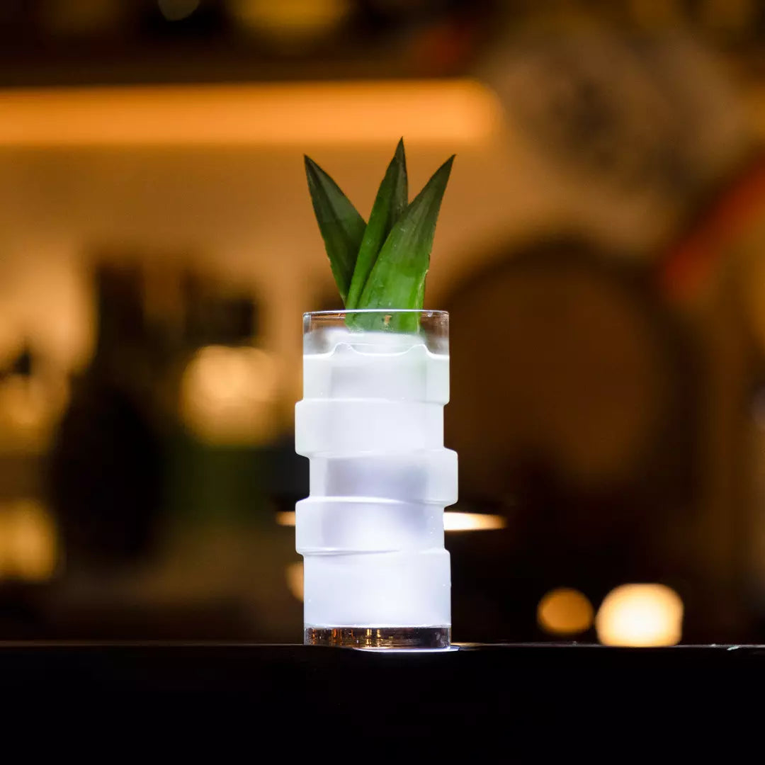 Cocktail in a frosted glass with a garnish on a bar counter.