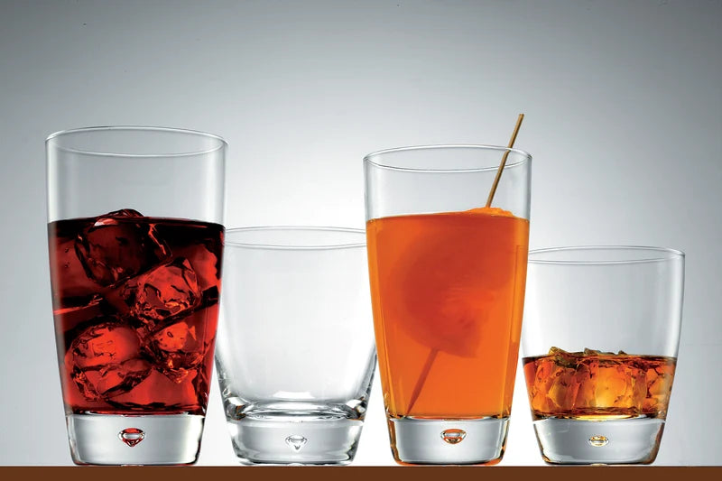 Four dimple shaped tumblers, two late and two small with liquids presented on a light grey background
