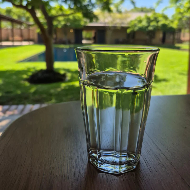 Clear glass of water on a wooden table with a garden background