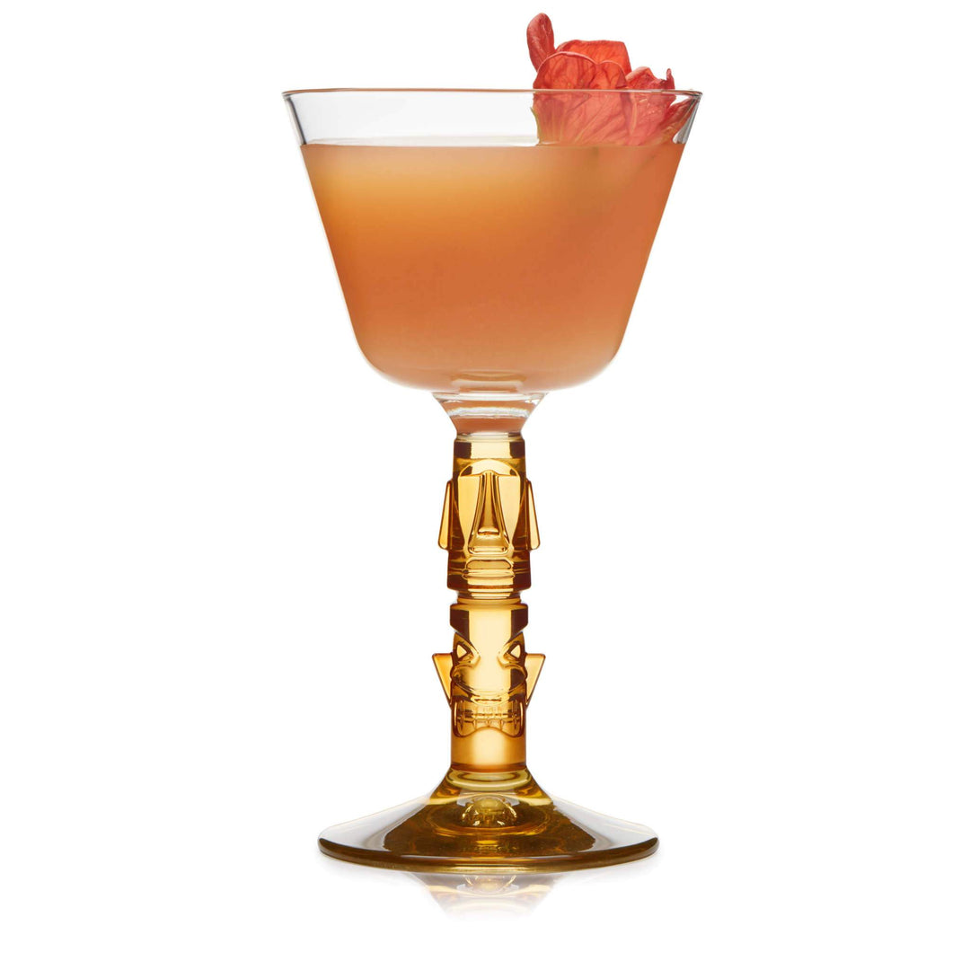 Coupe glass with orange liquid and flower on white background
