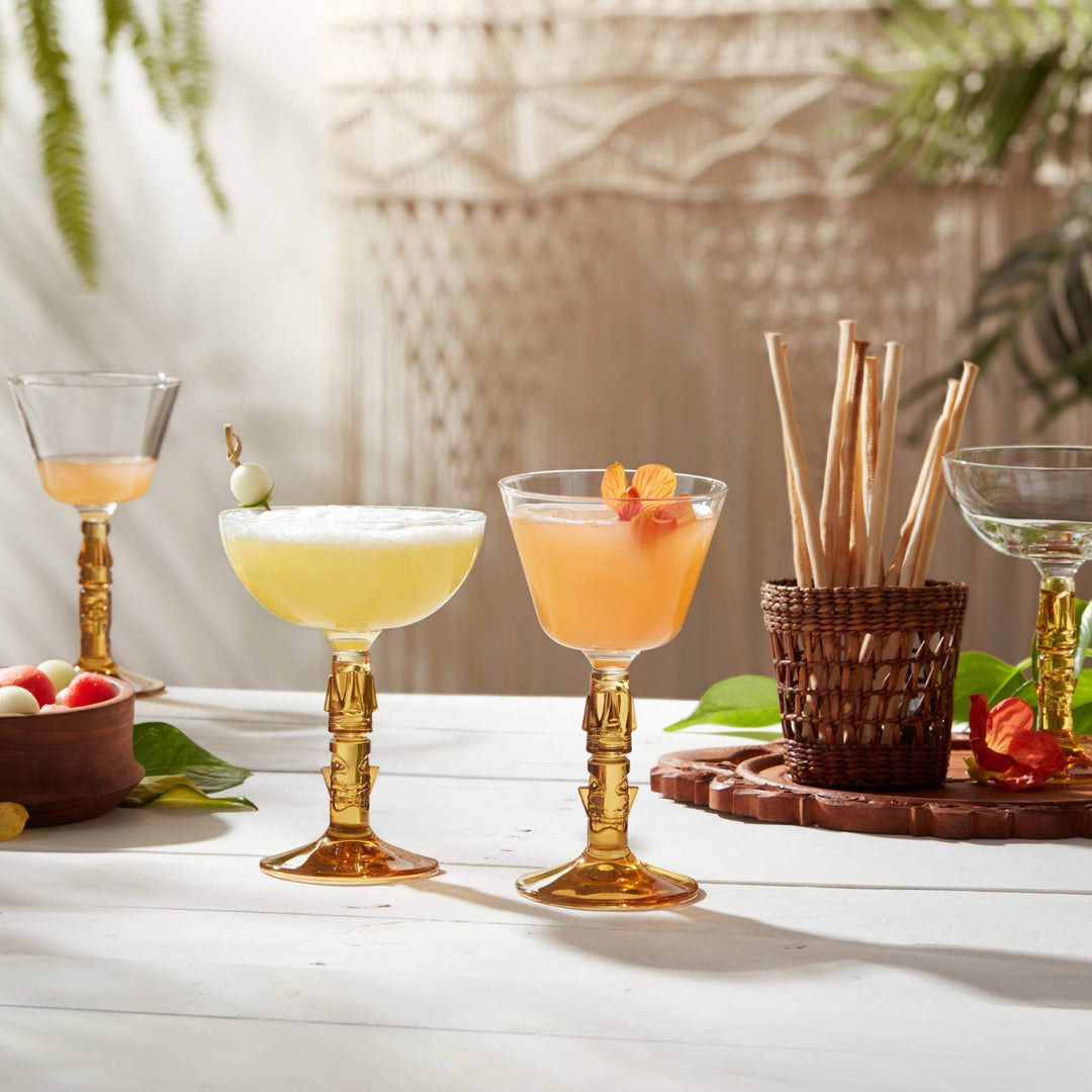 Four different coupe glasses on table with basket of bread sticks