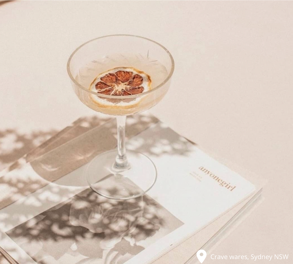 Champagne saucer with lemon inside on white background on top of a magazine