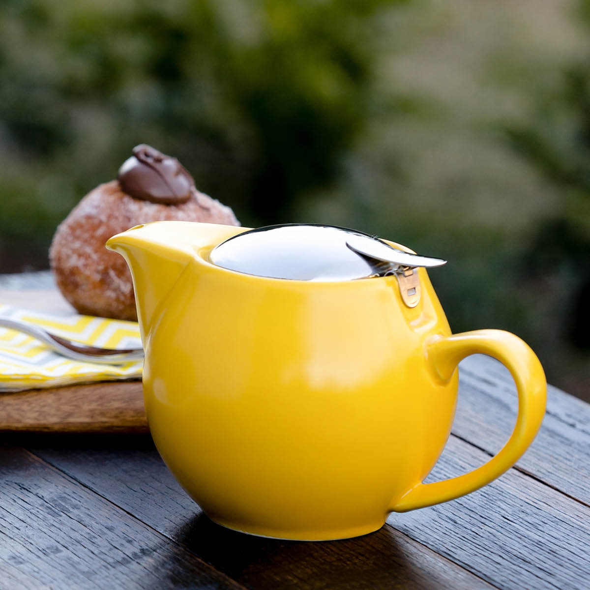 Yellow teapot on garden background