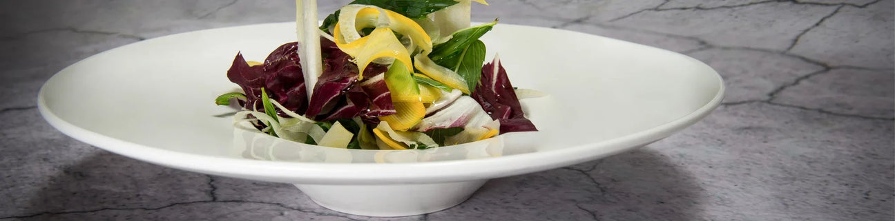 White salad bowl with lettuce leaves on marble background