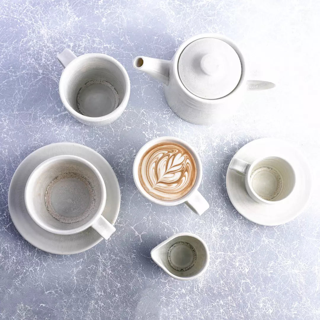White ceramic coffee set with a latte art design on a light gray surface