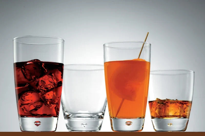 Four dimple shaped tumblers, two late and two small with liquids presented on a light grey background