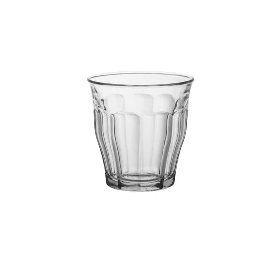 A clear glass tumbler with a textured, vertically fluted pattern, centered on a solid white background.