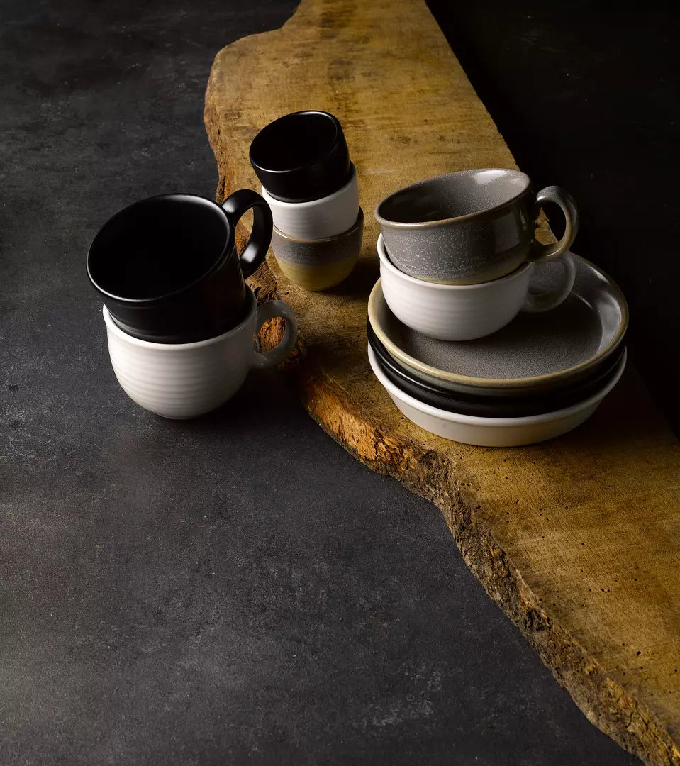 Different coloured cups and bowls on wood serving board on grey table