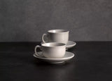 Two coffee cups and saucers on grey background