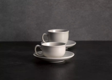 Two coffee cups and saucers on grey background