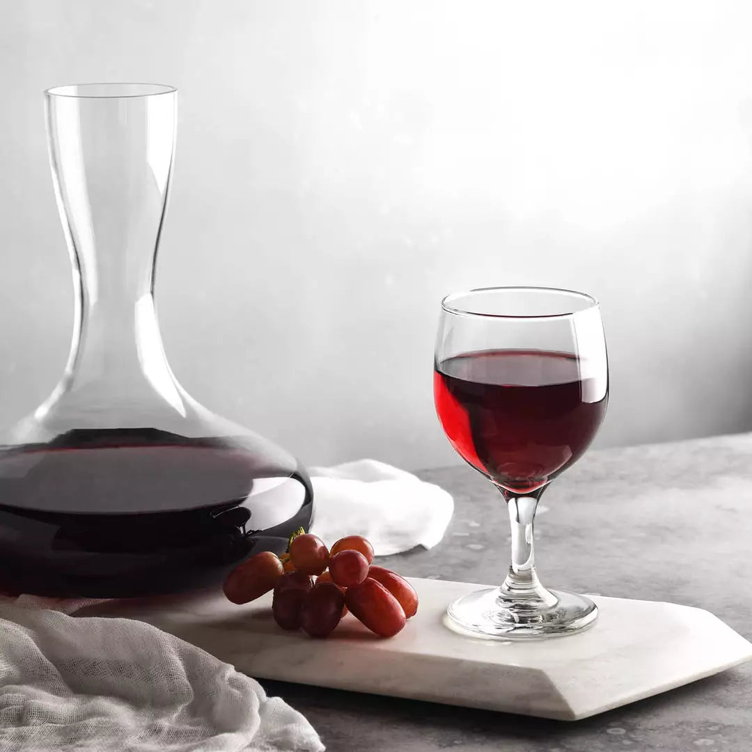 Wine decanter and glass with red wine on a marble surface