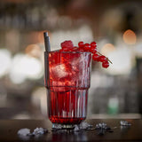 Red cocktail with berries and ice in a glass on a bar counter.