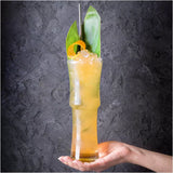 Cocktail with ice and garnish held by a hand against a dark textured background