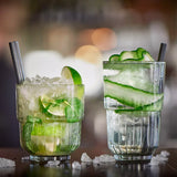 Two glasses of green cocktails with lime and cucumber slices on a blurred background