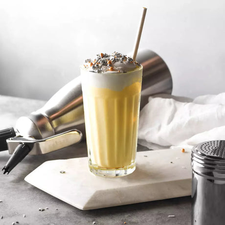 Large panelled tumbler with liquid and cream on top on a cafe style background