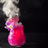 Pink cocktail with flowers and an umbrella on a dark background