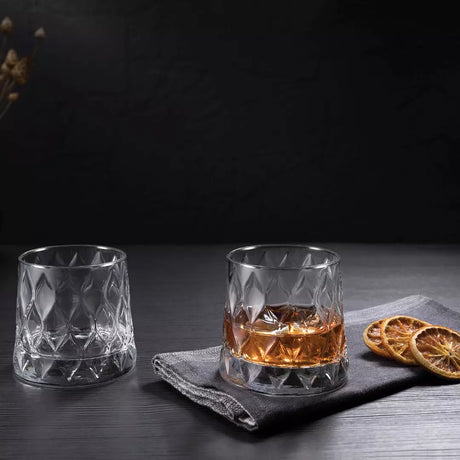 Two glass tumblers with a drink on a dark surface with a black background