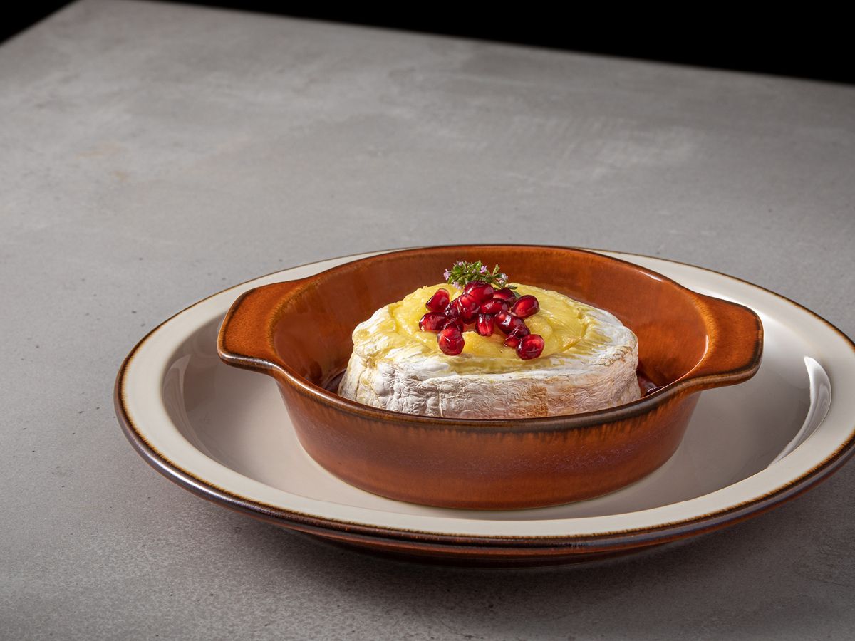 Brown Gratin dish with souffle on circular plate on grey table