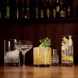 Various stylish glasses with liquids and garnish in a bar setting