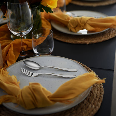 Table setting with spoon and fork on light blue speckled plate