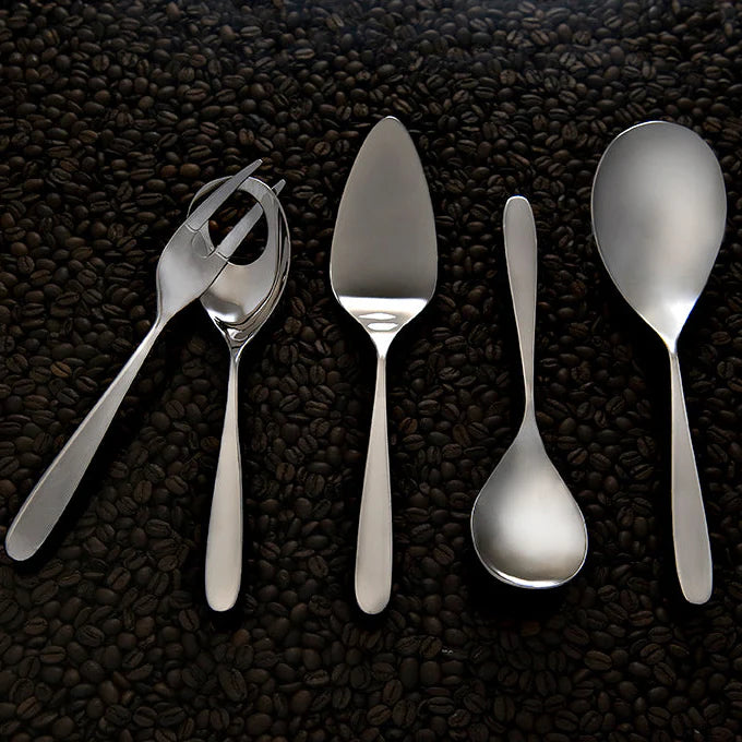 Set of silver utensils including a fork, knife, and spoons on a dark textured surface.
