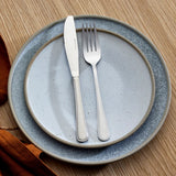 Set of silver knife and fork on a gray ceramic plate with a wooden background