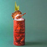 Tropical cocktail in a decorative Tiki glass with pineapple garnish on a teal background