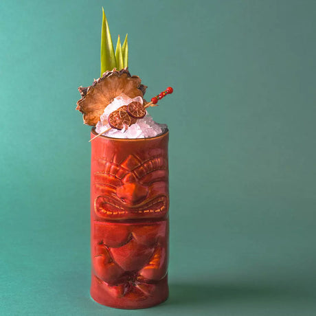 Tropical cocktail in a decorative Tiki glass with pineapple garnish on a teal background