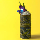Tiki mug with a cocktail and floral garnish on a yellow background