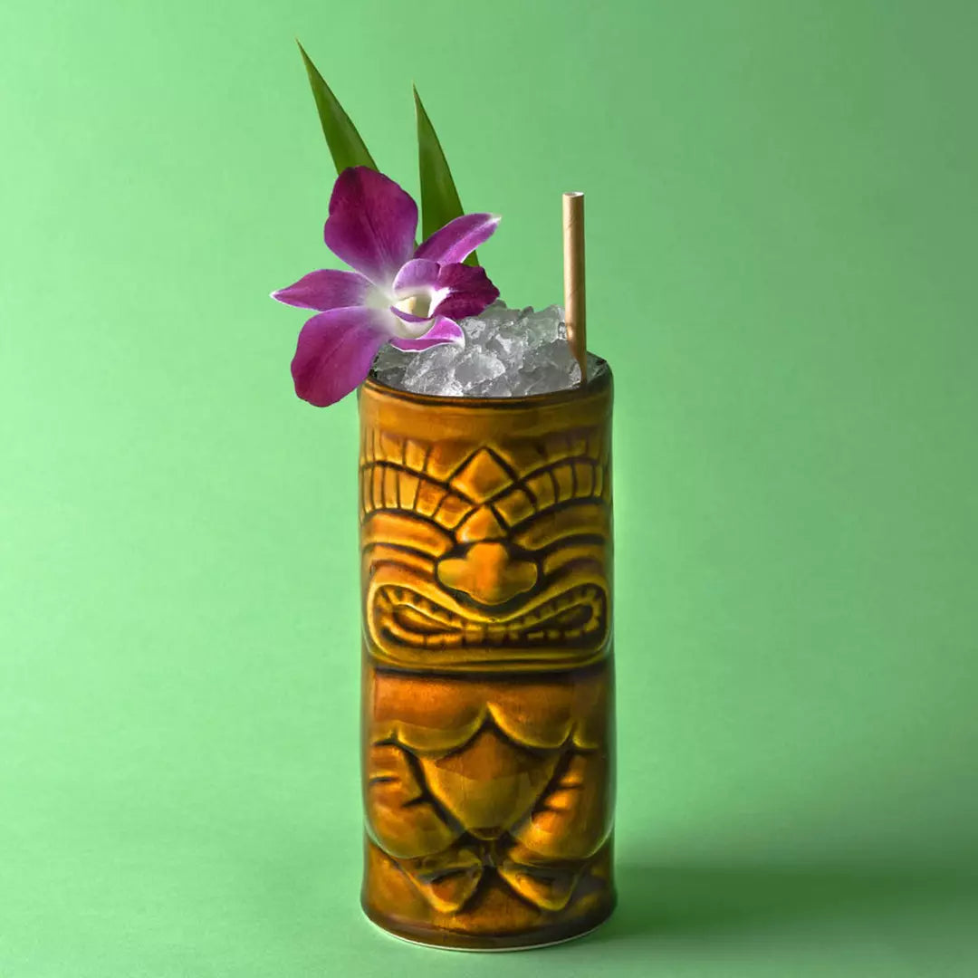 Tiki mug with a cocktail and purple flower on a green background
