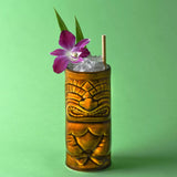 Tiki mug with a cocktail and purple flower on a green background