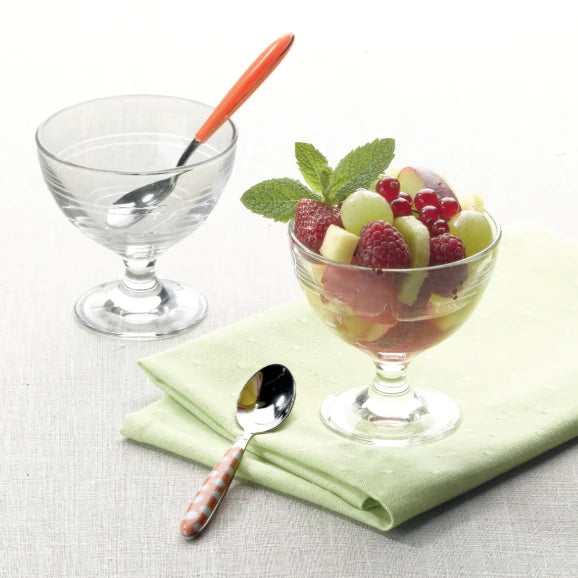 One clear and on dessert cup with fruit salad displayed on a white table setting