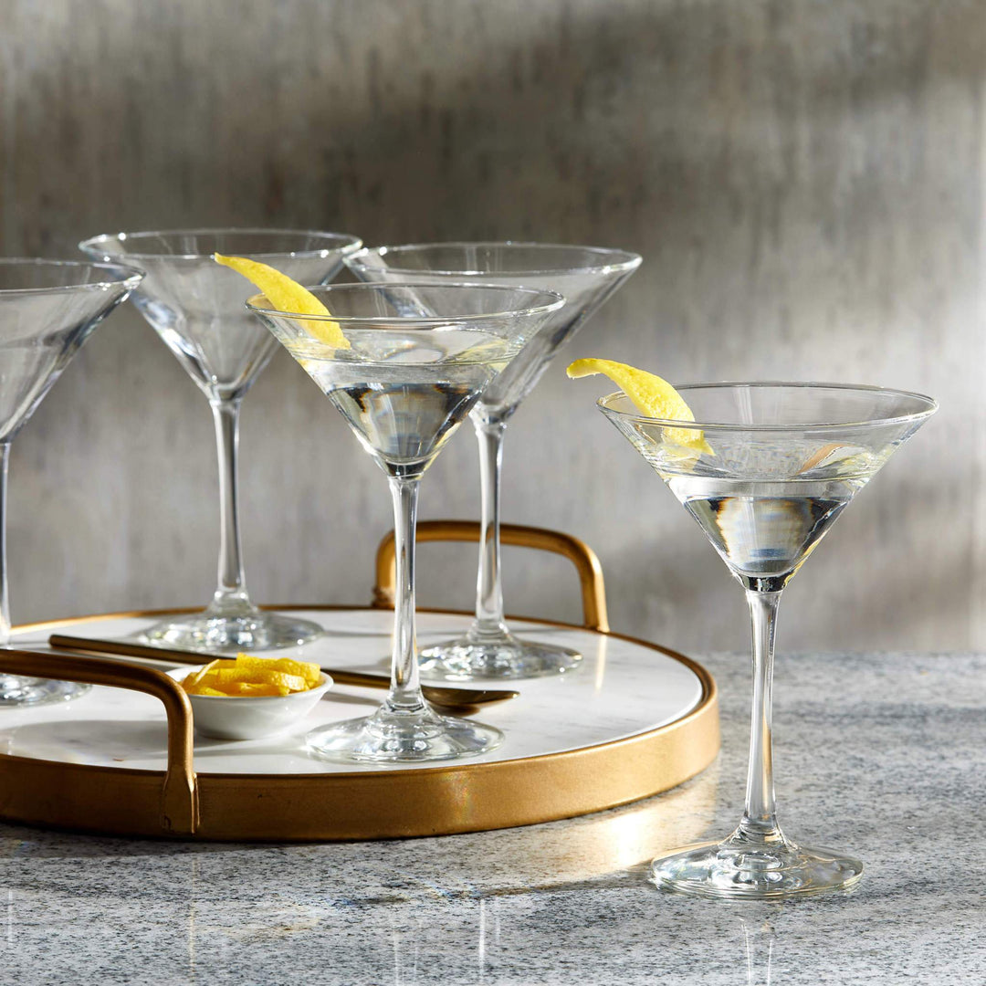 Four martini glasses with liquid and lemon garnish on round serving tray