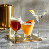Beer glass and two cocktail glasses with liquid in bar setting