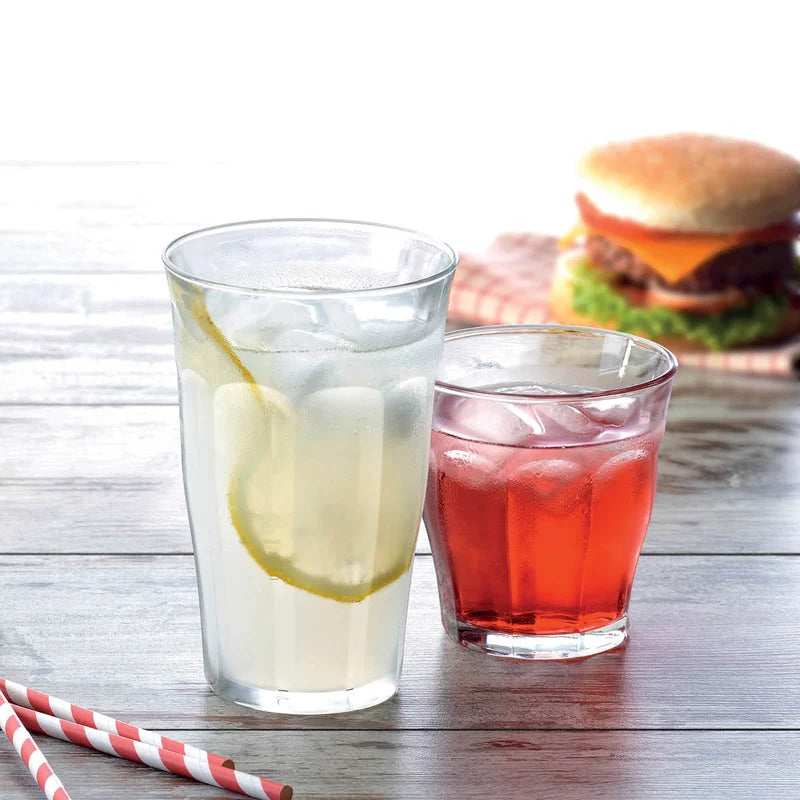 One large and one small tumbler is a restaurant setting with a burger in the background