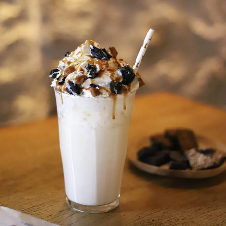 Glass of milkshake with whipped cream and cookies on a wooden table