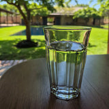 Clear glass of water on a wooden table with a garden background