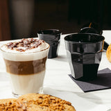 Medium sized tumbler showing a cafe late on a table setting with black plastic tumblers in background on a table setting