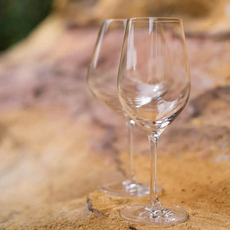 Two clear wine glasses on a textured surface