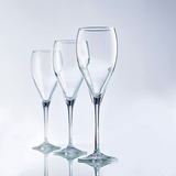 Three empty champagne flutes in front of one another fading into a light grey background