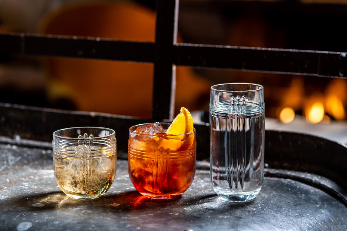 Three tumblers, small / medium and large all with liquid in a bar environment