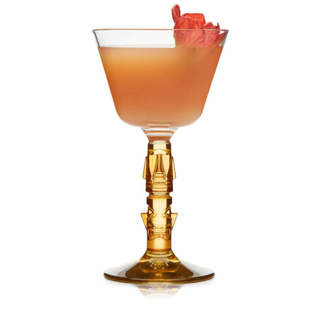 Coupe glass with orange liquid and flower on white background