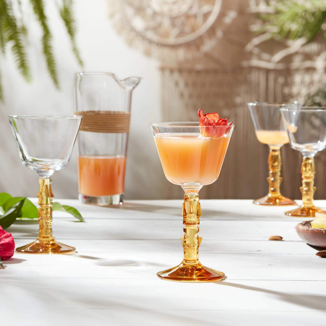 Four decorative coupe glasses with jug on table