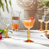 Four decorative coupe glasses with jug on table