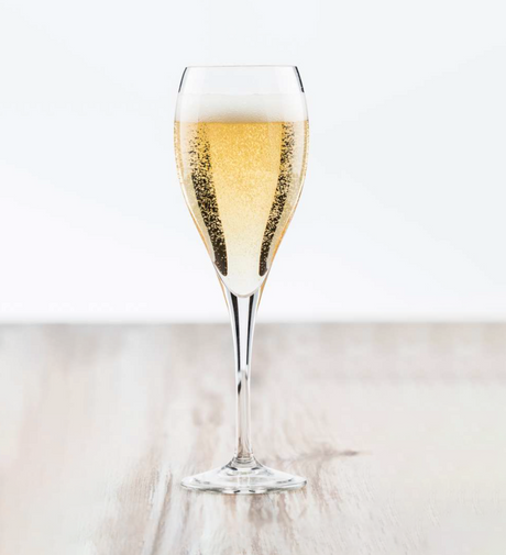 A standard sized champagne fulte with sparkly liquid on a white background