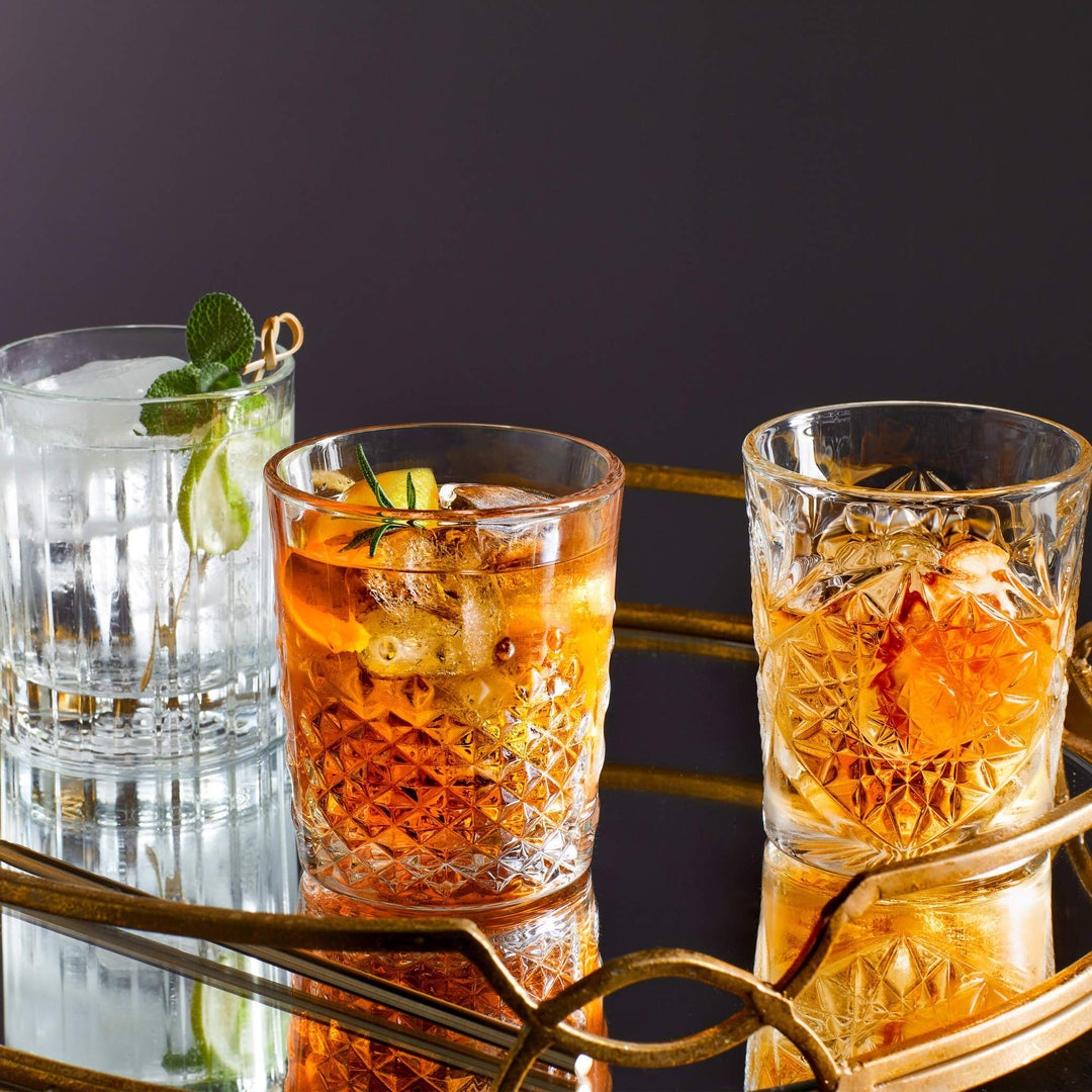 Three crystal cut glasses, all with liquid on bar trolley