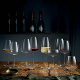 Nine different wine glasses on a wooden table setting