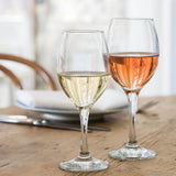 two wine glasses with liquid on table setting